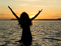 woman in the water with arms raised in happiness and prayer